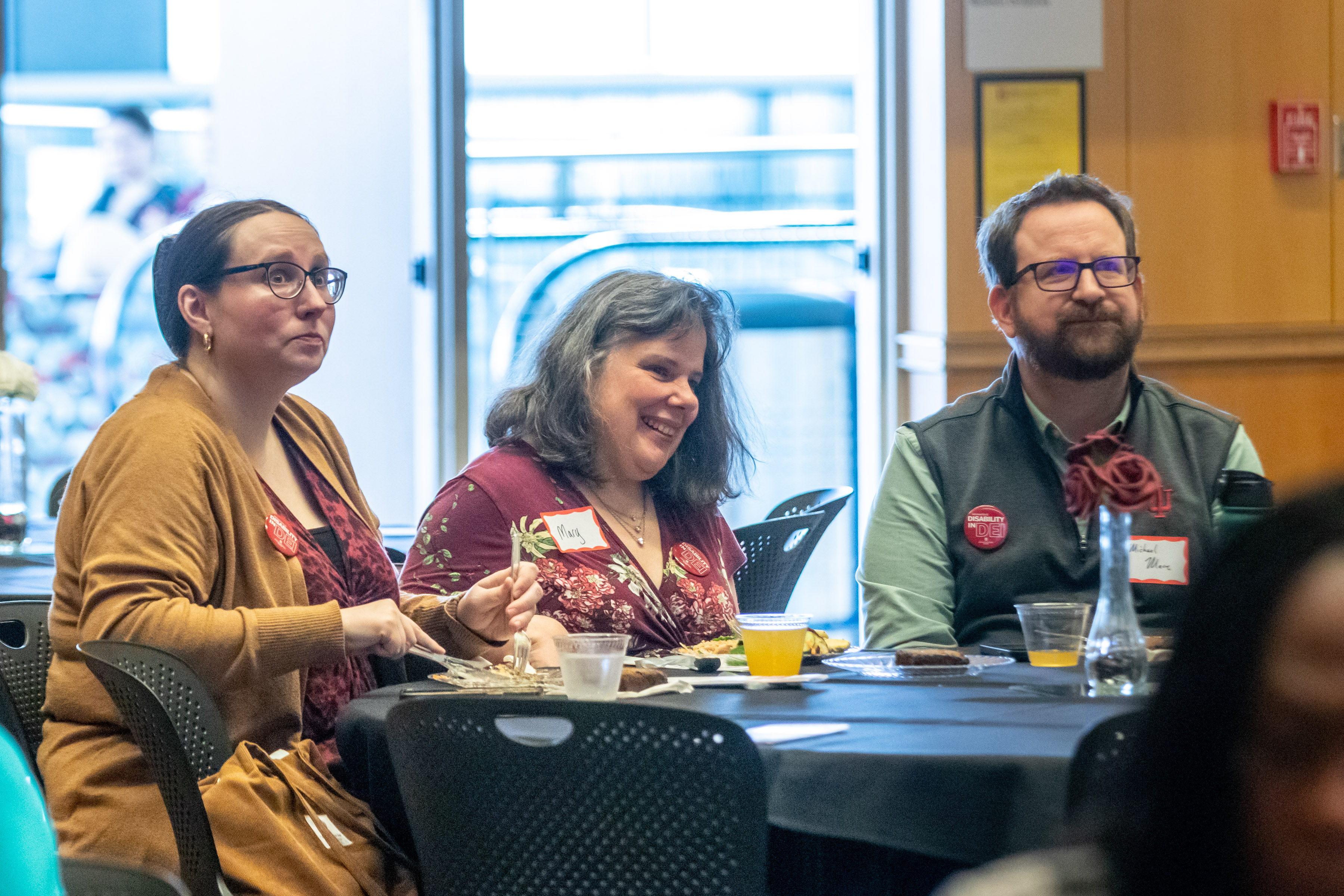 Three attendees at their table, all members of ATAC, looking on with eager expressions