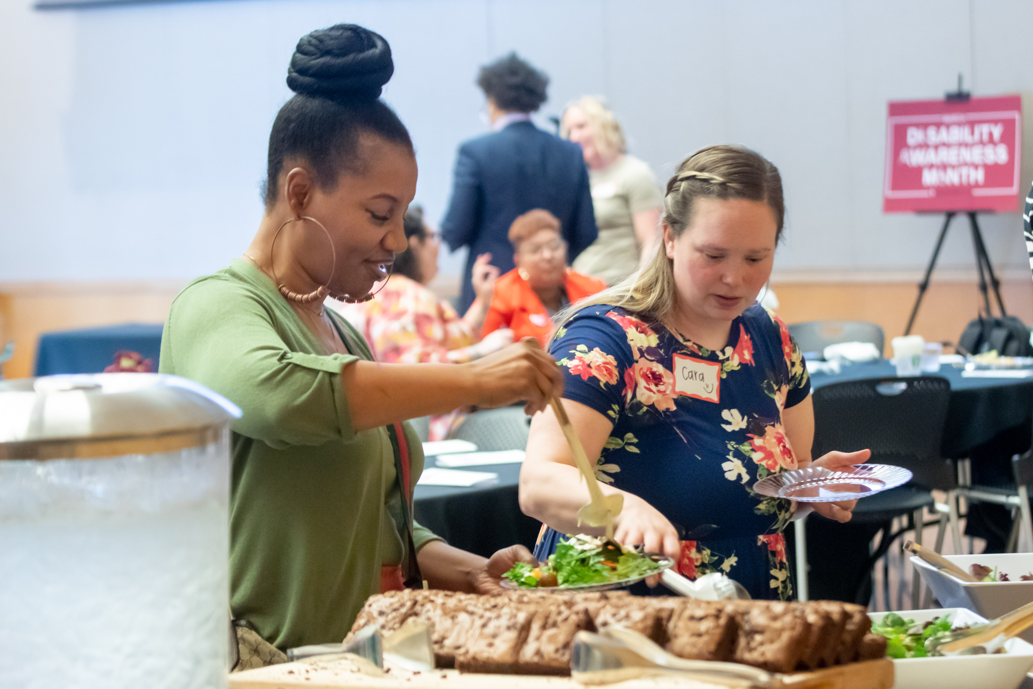 Two well dressed women smile as they select lunch options