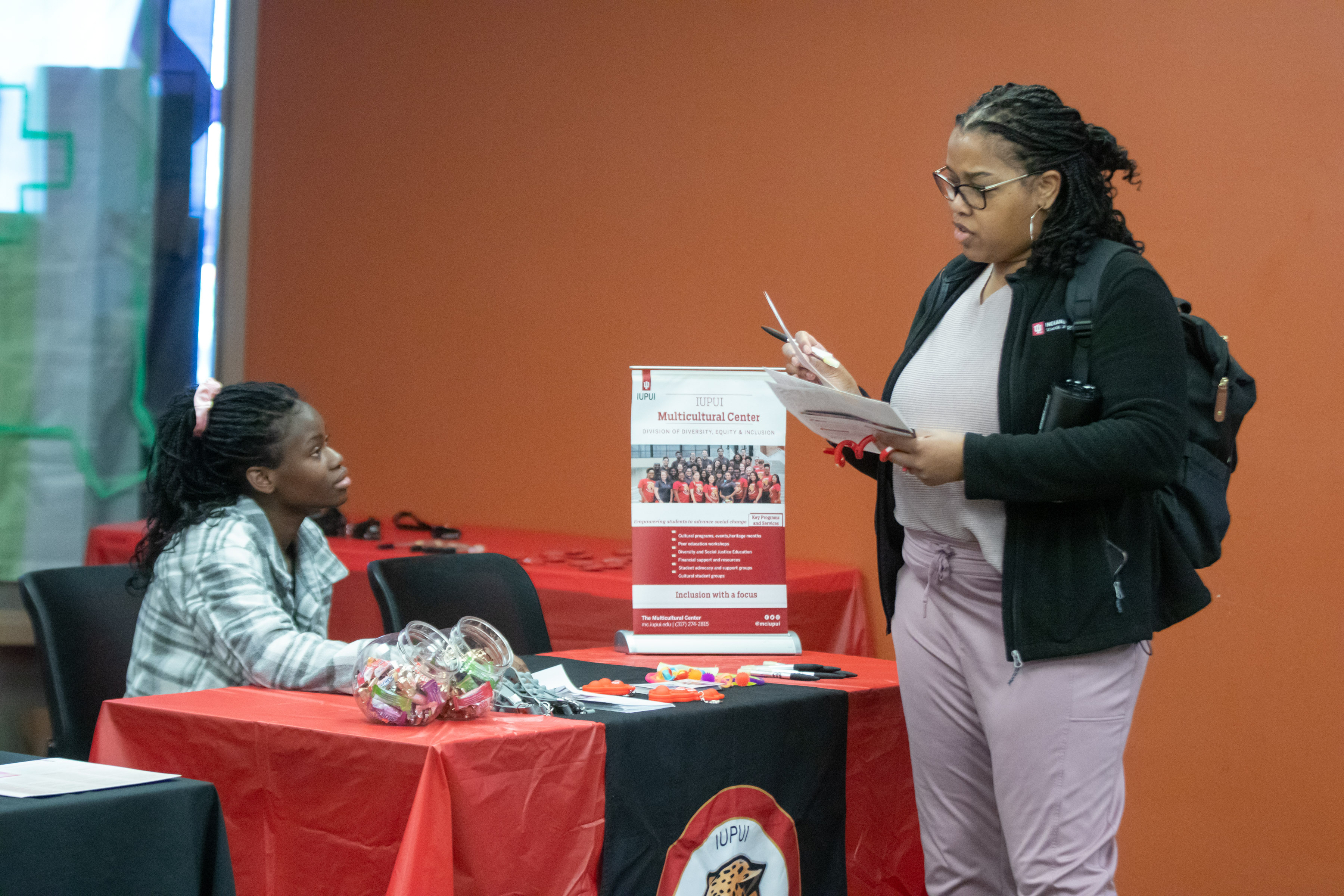 View of the Multicultural Center table where representative speaks to attendee holding a brochure