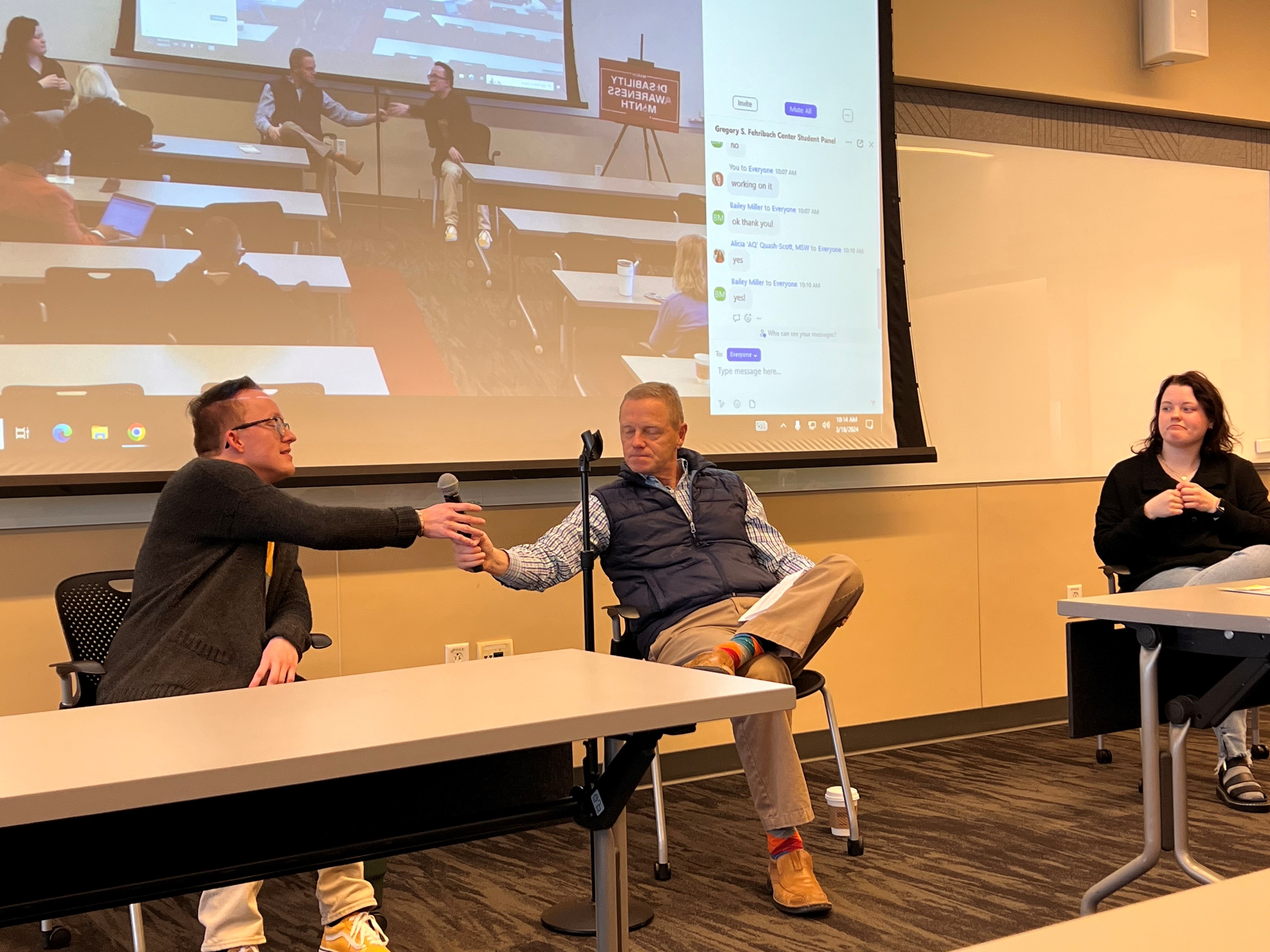 View of the panelist taking the microphone to answer a question from the host with ASL interpreter on the right